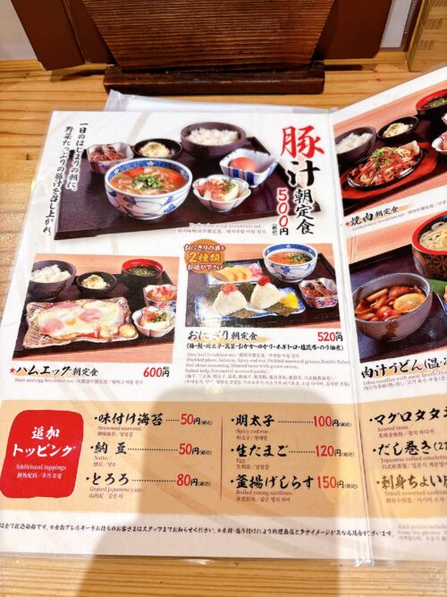 「ぎふや」の朝食メニュー表。主要な定食は「豚汁朝食 500円」、「おにぎり朝食 520円」、「ハムエッグ朝食 600円」の他、「焼肉定食 650円」や「お造り定食 780円」などがあり、トッピングメニューも記載されている。